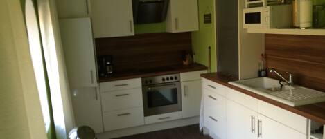A compact kitchen with white cabinets, a built-in oven, and a wooden countertop.