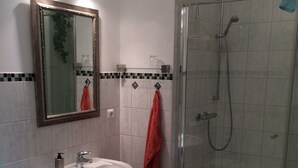 A bathroom with a white sink, mirror, and shower. - Vacation apartment in the tower  (Lehmkuhlen)