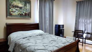 A bedroom with a bed, a desk, a chair, a television, and a painting on the wall.