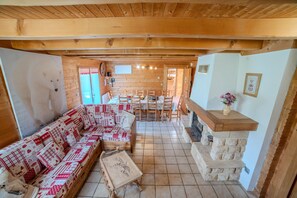 Un intérieur chaleureux, avec des murs en bois, un canapé, une table à manger, des chaises et une cheminée.