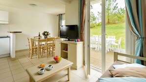 A cozy room with a dining table, chairs, a TV, and a balcony with outdoor seating. - Très belle maison de vacances | 1 km de la plage (Morgat)