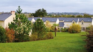 A row of houses with sloped roofs and a well-maintained lawn in the foreground. - Très belle maison de vacances | 1 km de la plage (Morgat)