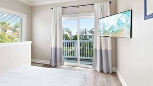 Una camera da letto con un letto, una porta vetrata scorrevole su un balcone e un televisore montato a parete.