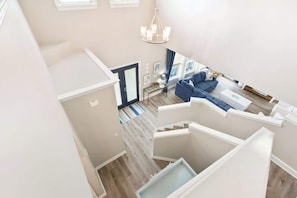 A multi-level interior with a staircase, a living area with a sofa, and a chandelier. - Wave on Wave by Stay on 30a (Seacrest)