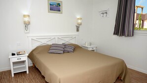 Un dormitori amb un llit, dues taules de nit i làmpades penjades a la paret.