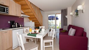 Un espacio habitable pequeño con cocina, comedor y un sofá rojo.