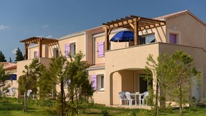 Un edificio de varios pisos con mesas al aire libre y una pérgola.