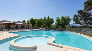 Une piscine au design incurvé, entourée de chaises longues et d’une clôture.