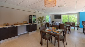 A modern kitchen with a dining area, large windows, and a television.