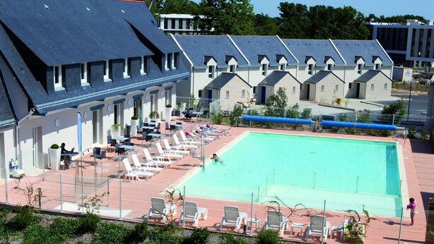 A hotel with a swimming pool, lounge chairs, and a covered patio area. - Appartement spacieux | Accès piscine (PLESCOP)