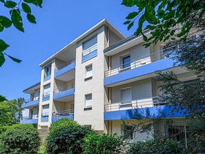 Un edificio residencial de varios pisos con balcones, ventanas y cielo despejado.