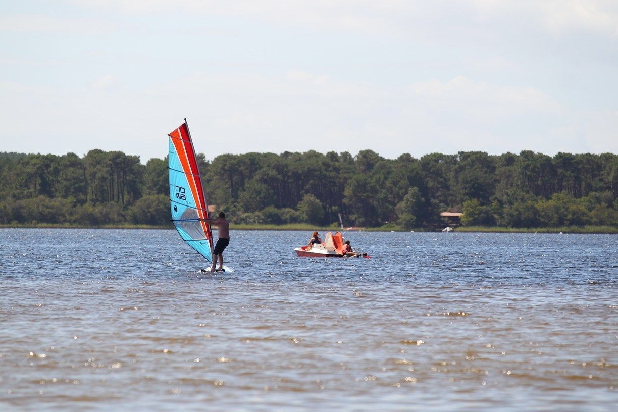 A person windsurfing on a lake with a boat in the background.