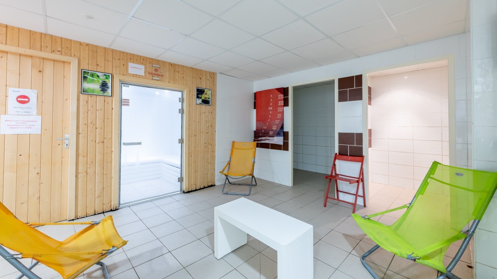 Une salle d’attente avec des murs en bois, un banc blanc et trois chaises.