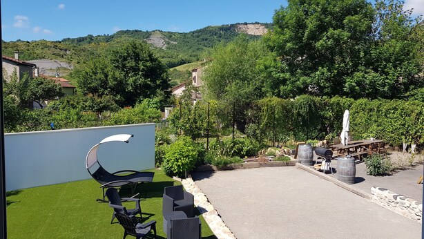 A patio with outdoor furniture, a barbecue grill, and a view of a hillside.