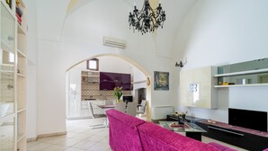 Een ruime woonkamer met een moderne keuken, een eethoek en een lichte kroonluchter.