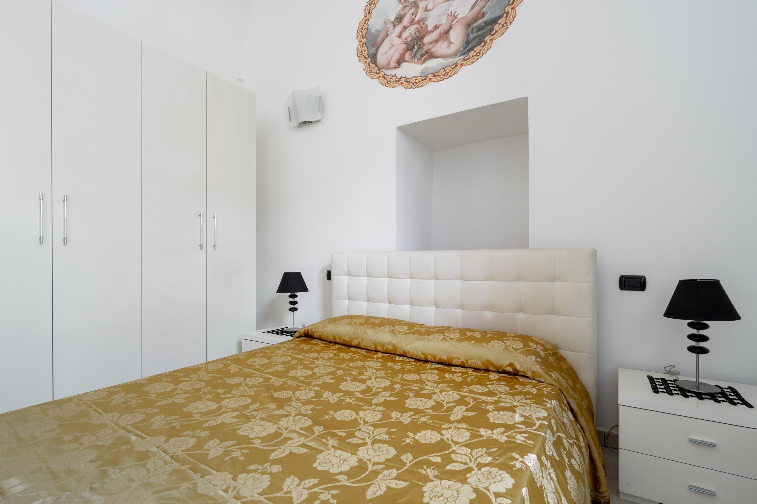 Une chambre à coucher comprenant un lit, une armoire, une table de chevet avec une lampe et un climatiseur fixé au mur.