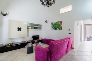 Una sala de estar moderna con un sofá, televisión y una mesa de comedor con un florero y un cuenco.