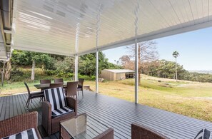 Un espace extérieur aménagé, abrité et doté de mobilier en osier, offrant une vue sur le paysage environnant.