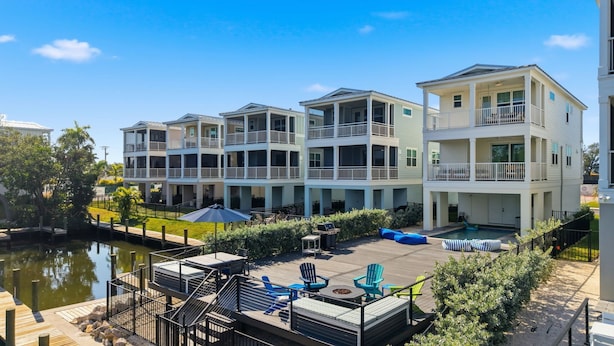 Edificio residenziale sul lungomare con numerosi balconi, un molo e area salotto esterna.