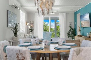 A dining area with a wooden table set for four, surrounded by upholstered chairs with leaf patterns.