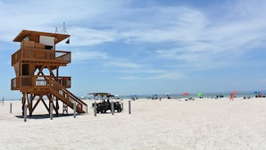 Una torre di salvataggio in legno con una scala su una spiaggia sabbiosa.