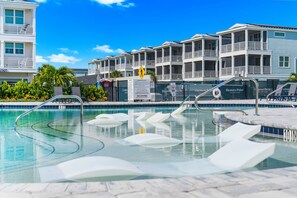A swimming pool with clear water, surrounded by lounge chairs and a building with balconies. - ⚓Eco-Home | Heated Pool, Boat Slip, Fire Pit & Elevator + Min to AMI⚓ (Bradenton)
