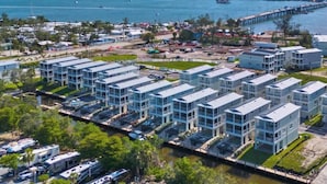 Una zona residenziale sulla costa, con moderni palazzi a schiera, un porto turistico e un ponte.