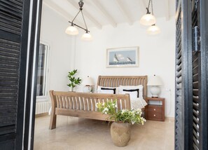 Et soveværelse med en træseng, et natbord, en potteplante, et vindue og et billede på væggen.