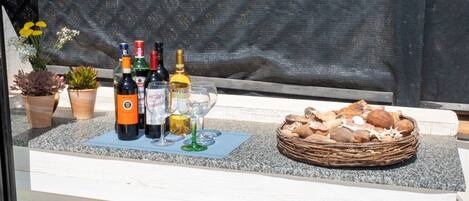 A bar area with bottles of wine, glasses, and a basket of nuts.
