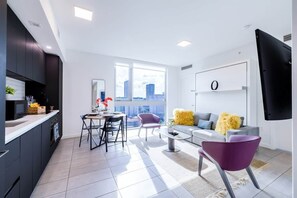 A modern apartment with a kitchen, dining area, living room, and a large window with a city view.