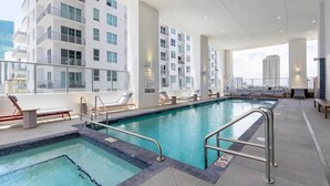 A rooftop pool with a view of high-rise buildings, lounge chairs, and a clear sky. - Skyline View Condo with Pool (Miami)