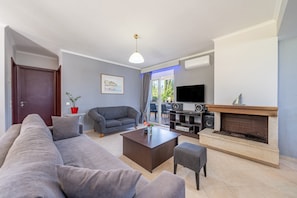 Una sala de estar con sofá, mesa de centro, chimenea y televisor.