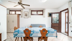 Een eetgedeelte met een tafel gedekt voor vier personen, een plafondventilator en een raam met gordijnen.