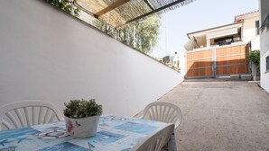 Een terras met een tafel, stoelen en een bloempot.