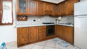 Een keuken met houten kastjes, een witte koelkast, een fornuis en een betegelde spatwand.