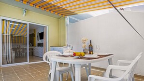 A dining area with a round table, white chairs, and a striped ceiling.
