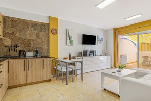 A modern kitchen with a dining area, a flat-screen TV, and a sofa in a bright living space. - Vacation Apartment 'La Octava Isla' with Shared Pool, Wi-Fi (Puertito de Güimar)