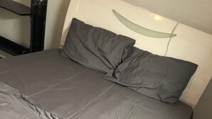 Una cama con ropa de cama gris y cabecera de diseño curvo.