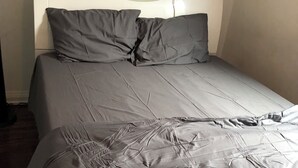 Una cama con ropa de cama gris y cabecera de diseño curvo.