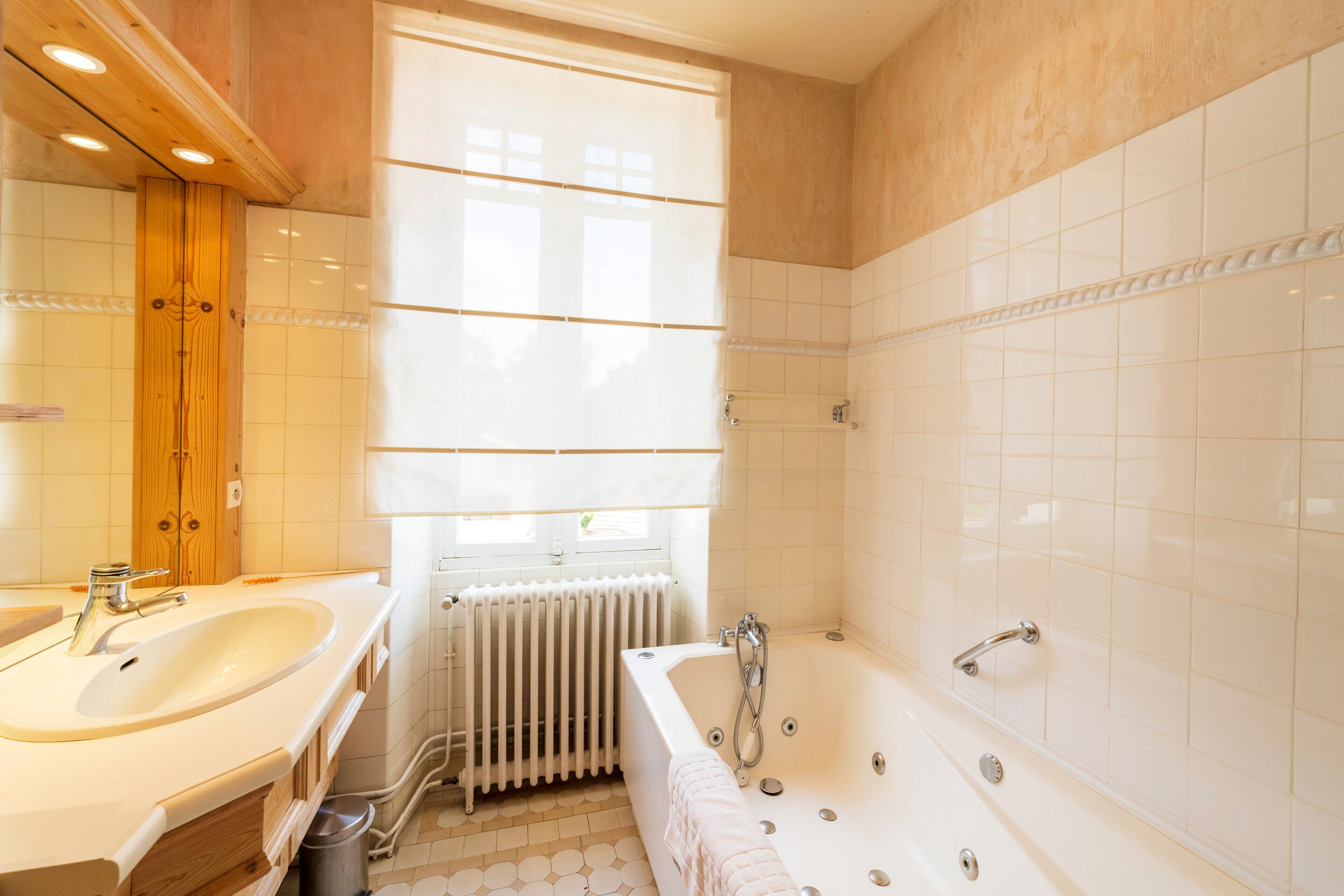 Un bagno con lavandino, vasca e finestra con persiane.
