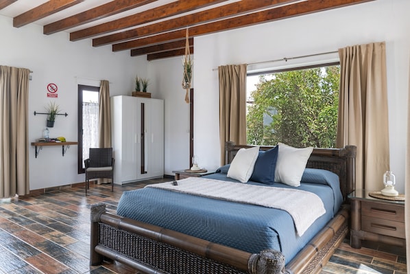 A bedroom with a wooden bed, a nightstand, a chair, a wardrobe, and a window with curtains.