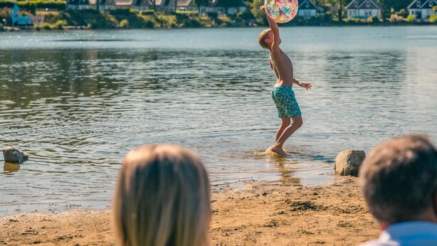 Una persona jugando con un disco volador en un lago.