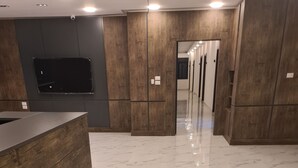 A modern hotel lobby with a marble floor, wooden reception desk, and a corridor leading to other rooms. - Royal House (Irbid)