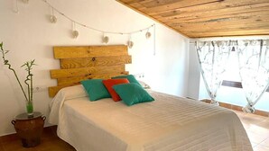 A bedroom with a wooden headboard, a bed with white bedding, and a potted plant.