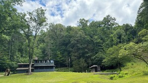 A rustic cabin with a large water wheel, surrounded by lush greenery and dense forest. - Charming & Historical 3-bedroom cabin in marvelous Franklin with AC, fast WiFi (Franklin)