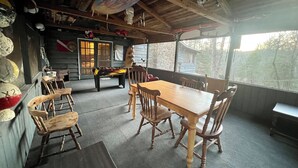 A rustic wooden interior with a dining table and chairs, a bench, and a surfboard decoration. - Charming & Historical 3-bedroom cabin in marvelous Franklin with AC, fast WiFi (Franklin)