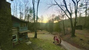 A rustic cabin with a stone exterior, a wooden deck, and a fenced yard with a trampoline. - Charming & Historical 3-bedroom cabin in marvelous Franklin with AC, fast WiFi (Franklin)