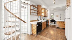 A modern kitchen with a spiral staircase, wooden cabinets, and a central island.