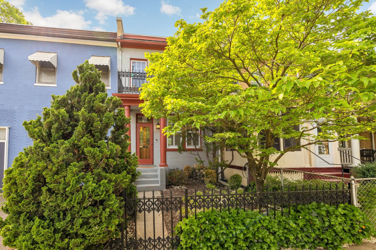 A two-story house with a red door and a balcony.