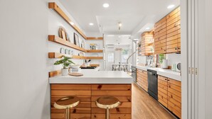 A modern kitchen with wooden cabinets, a white countertop, and two stools.